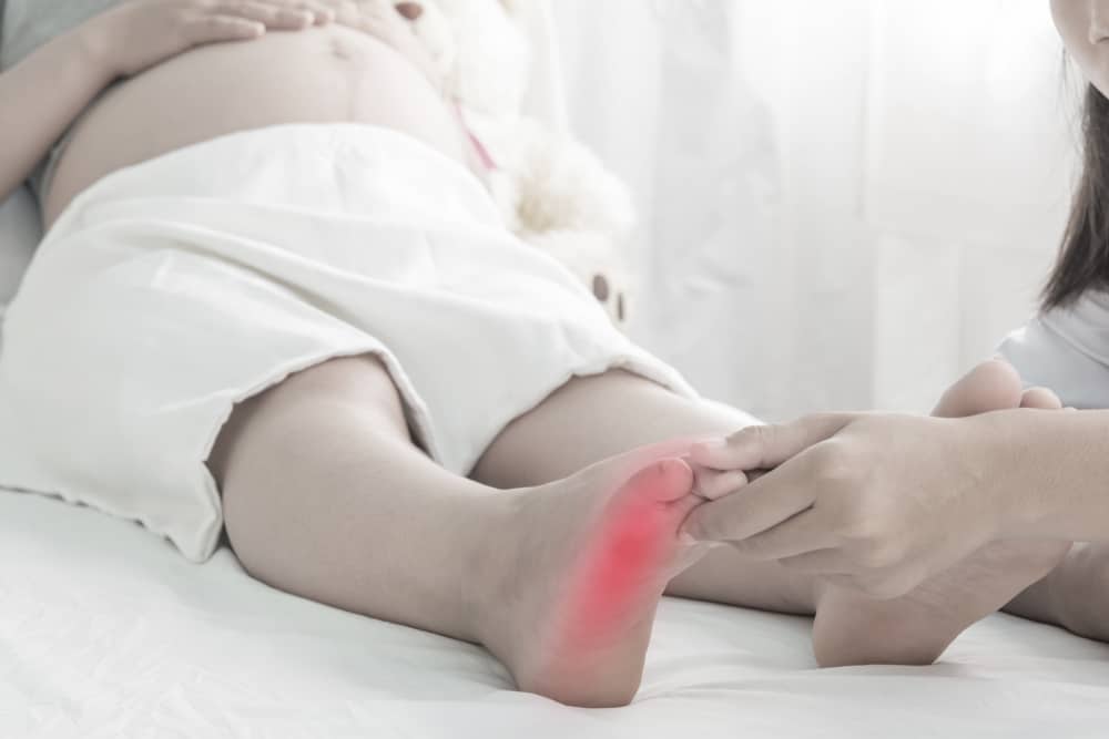 Foot swelling of pregnant women on bed and doctor