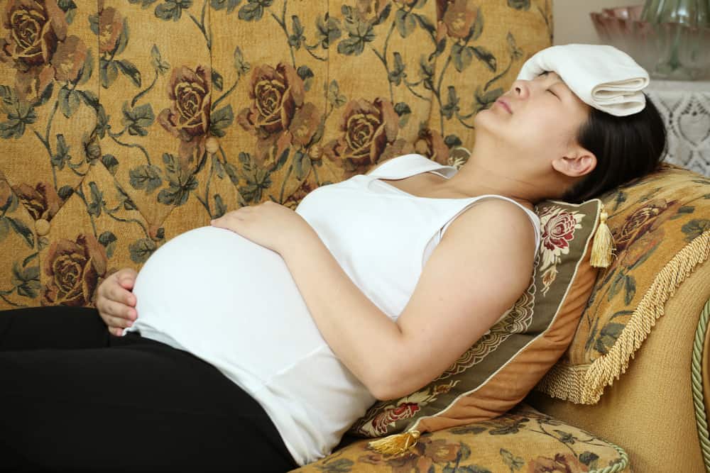 Suffering pregnant woman stupes towel to her head